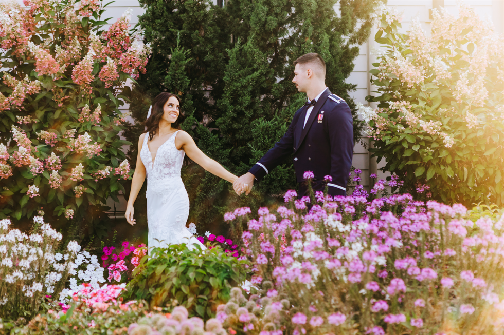 groom and bride walk by a white split rail fence
